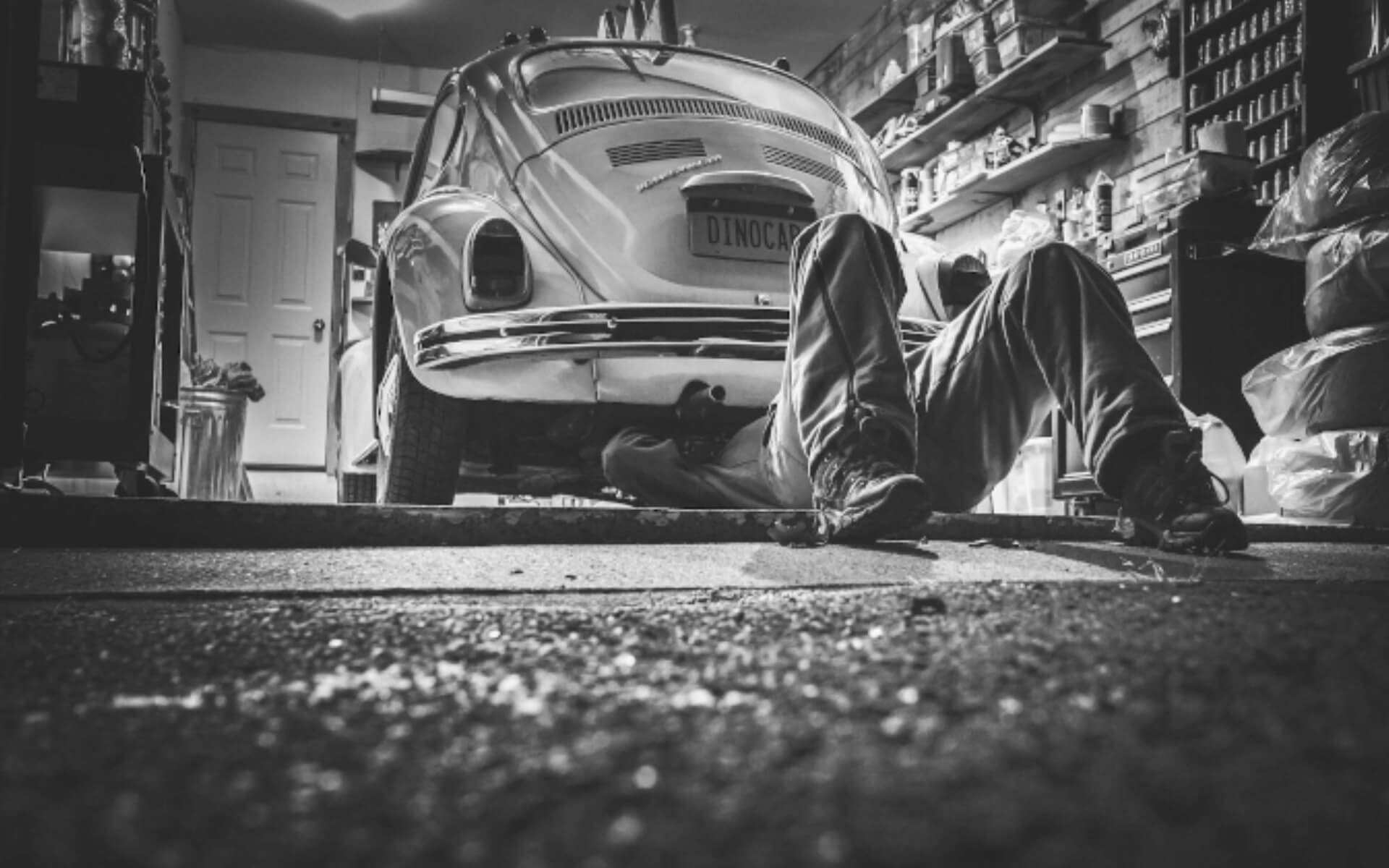 Mechanic lies under a 1960s Volkswagen Beetle in a garage